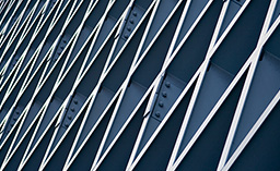 An abstract, close-up shot of a modern architectural facade featuring a diagonal lattice of silver or white metal beams over deep blue panels.
