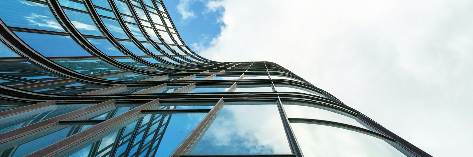 A modern, curved skyscraper rises toward the sky, symbolizing the concept of elevating investments and financial growth.