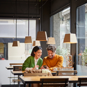 Middle aged man and woman sitting in a cafe smiling at a phone