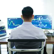 Man looking at charts on computer screens